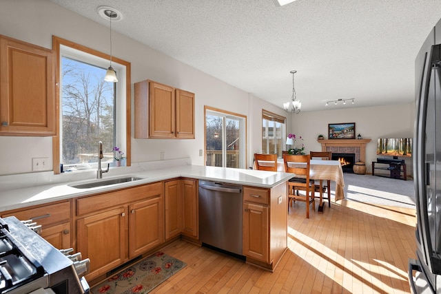 kitchen featuring stainless steel appliances, a sink, light wood-type flooring, a chandelier, and light countertops
