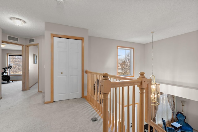 corridor featuring carpet flooring, a textured ceiling, an upstairs landing, and baseboards
