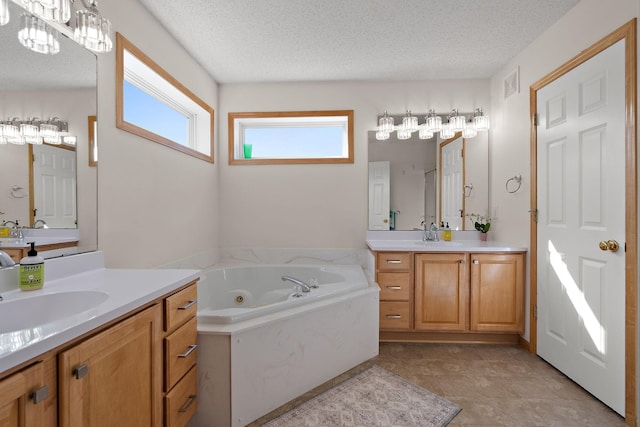 full bathroom with a textured ceiling, a jetted tub, and two vanities