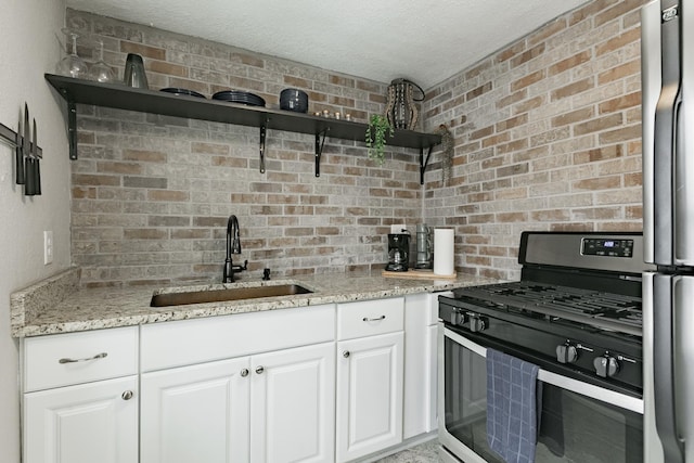 1541 Charles Ave, Saint Paul, MN 55104 - kitchen with appliances with stainless steel finishes, a sink, open shelves, light stone counters, and white cabinets