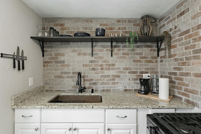 1541 Charles Ave, Saint Paul, MN 55104 - kitchen with a sink, open shelves, range with gas stovetop, a textured ceiling, and white cabinets