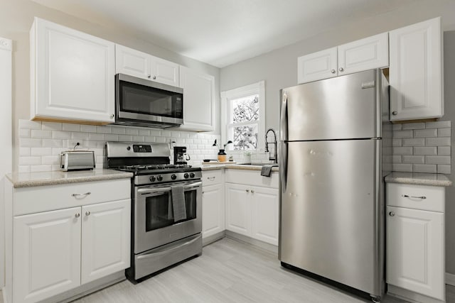 1541 Charles Ave, Saint Paul, MN 55104 - kitchen featuring appliances with stainless steel finishes, a sink, backsplash, white cabinetry, and light floors