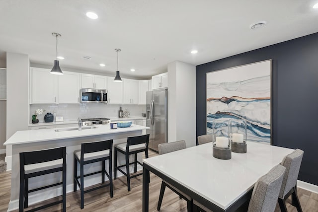 dining space with light wood-style flooring, recessed lighting, and baseboards