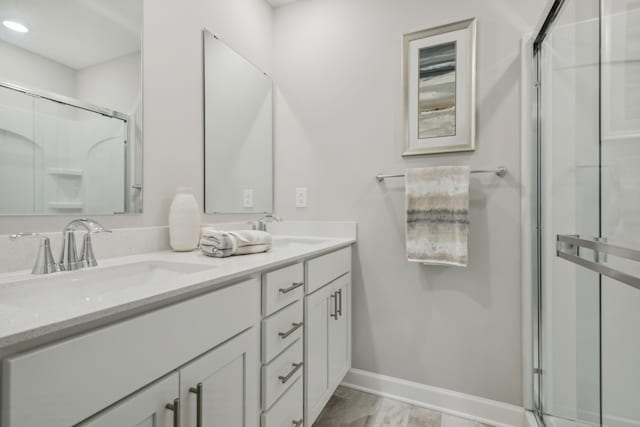 bathroom with an enclosed shower, baseboards, and double vanity