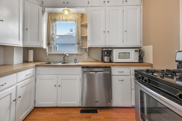 110 7th St SE, Little Falls, MN 56345 - kitchen featuring appliances with stainless steel finishes, a sink, white cabinetry, and light wood-style flooring