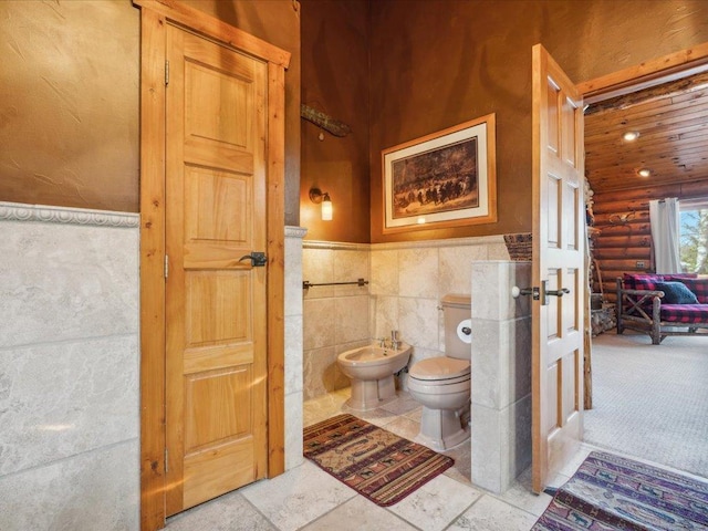 15464 Birch Narrows Rd, Crosslake, MN 56472 - bathroom featuring log walls, a bidet, toilet, wainscoting, and tile walls