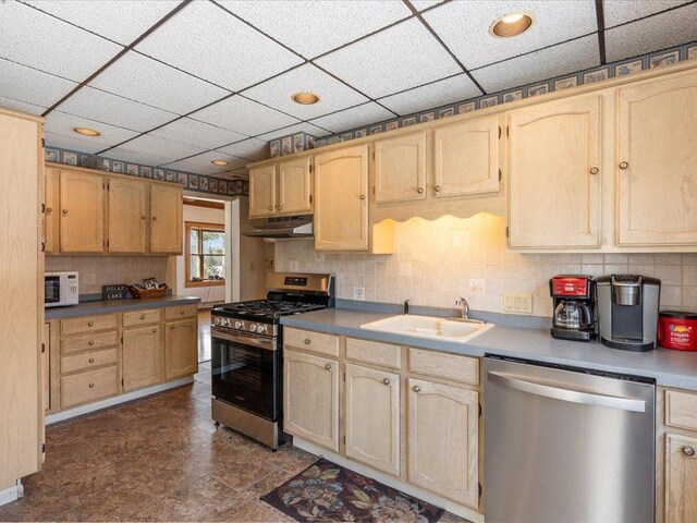 kitchen featuring stainless steel appliances, a sink, under cabinet range hood, decorative backsplash, and light brown cabinetry