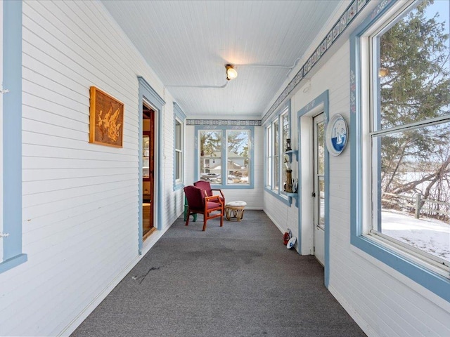 sunroom / solarium with carpet flooring and wood walls