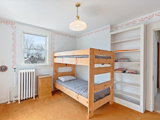 bedroom with radiator, light colored carpet, and a textured ceiling