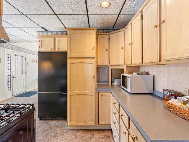 712 Cleveland Blvd W, Walker, MN 56484 - kitchen featuring freestanding refrigerator, white microwave, light brown cabinetry, a drop ceiling, and backsplash
