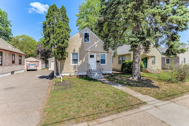 bungalow-style house with a garage, an outdoor structure, stucco siding, and a front yard