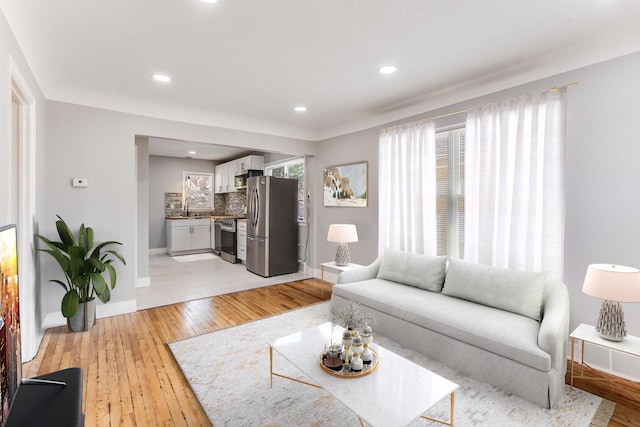living area featuring light wood-style flooring, baseboards, and recessed lighting