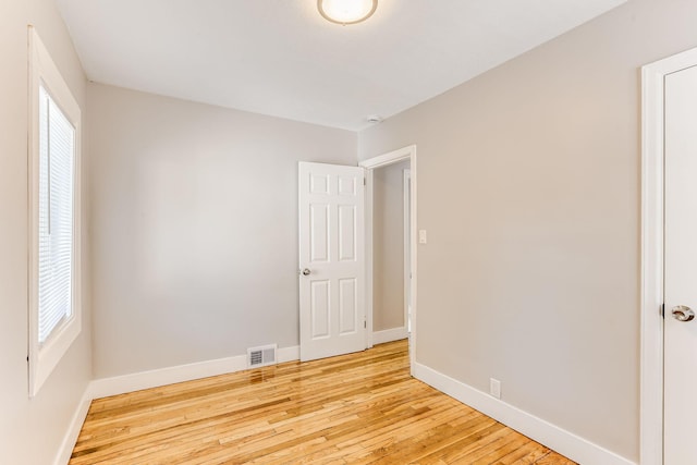 empty room featuring baseboards, light wood-style flooring, and healthy amount of natural light