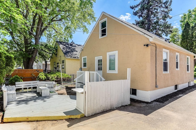 back of house with a deck, stucco siding, and fence