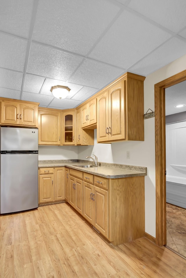 809 3rd Ave SE, Cold Spring, MN 56320 - kitchen featuring freestanding refrigerator, light wood finished floors, a sink, glass insert cabinets, and a drop ceiling