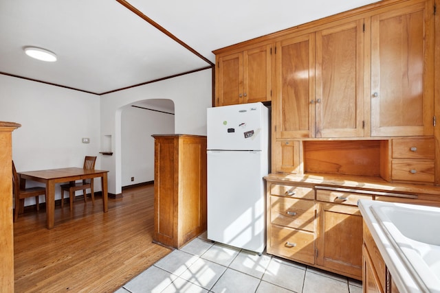 5028-5030 Nicollet Ave S, Minneapolis, MN 55419 - kitchen featuring freestanding refrigerator, arched walkways, brown cabinetry, a sink, and light countertops