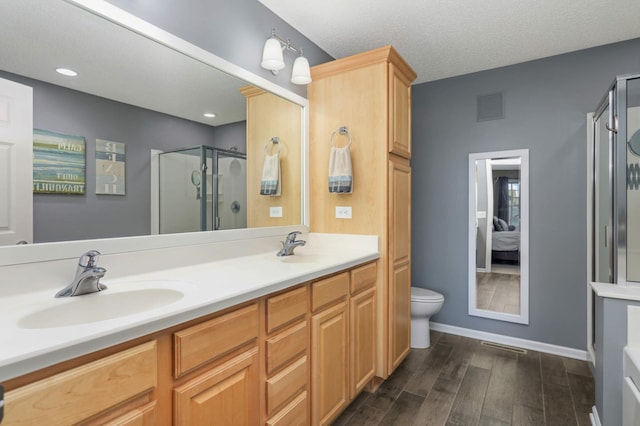 4323 Victor Path Unit 1, Hugo, MN 55038 - ensuite bathroom featuring a shower stall, toilet, double vanity, wood finished floors, and baseboards