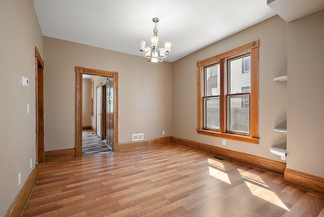 2911 California St NE, Minneapolis, MN 55418 - empty room with light wood finished floors, a chandelier, and baseboards