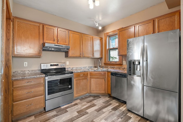 2911 California St NE, Minneapolis, MN 55418 - kitchen featuring appliances with stainless steel finishes, under cabinet range hood, a sink, light wood-type flooring, and brown cabinetry