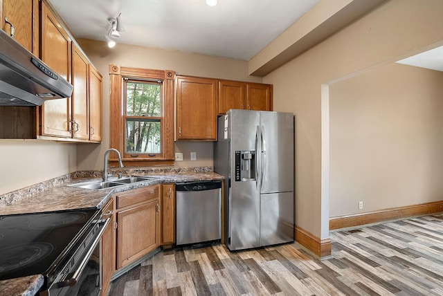 2911 California St NE, Minneapolis, MN 55418 - kitchen with appliances with stainless steel finishes, under cabinet range hood, a sink, light wood finished floors, and brown cabinetry
