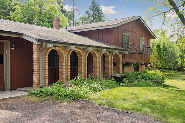 1031 Pheasant Trl, Hudson, WI 54016 - view of property exterior with brick siding, board and batten siding, a lawn, a chimney, and roof with shingles