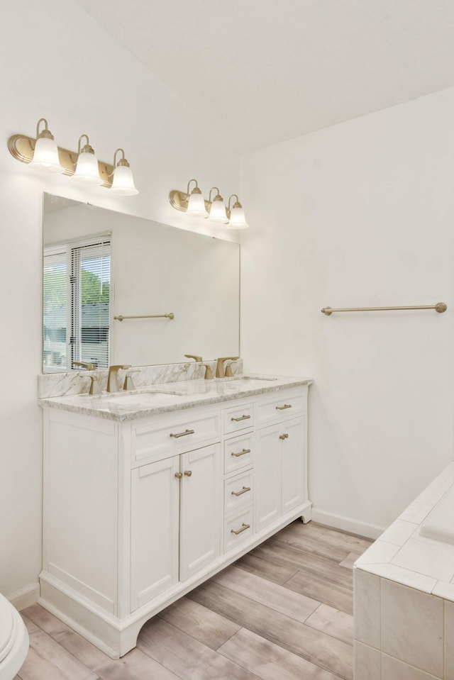 12625 Tiffany Ct, Burnsville, MN 55337 - bathroom with wood finished floors, double vanity, baseboards, and tiled bath