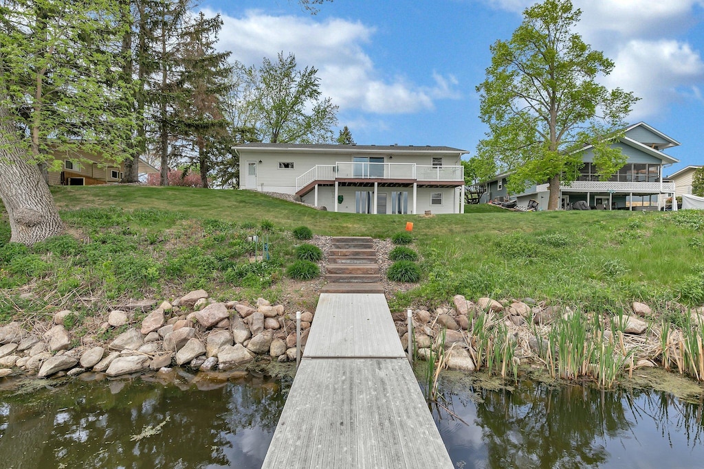 17605 Finch Ct, Cold Spring, MN 56320 - back of house featuring stairway, a lawn, a deck with water view, and a sunroom