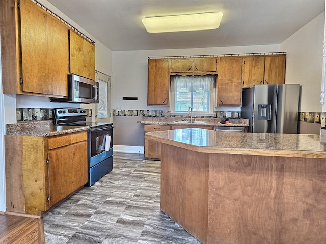 1501 Park St, Fairmont, MN 56031 - kitchen featuring appliances with stainless steel finishes, brown cabinetry, a sink, and a peninsula