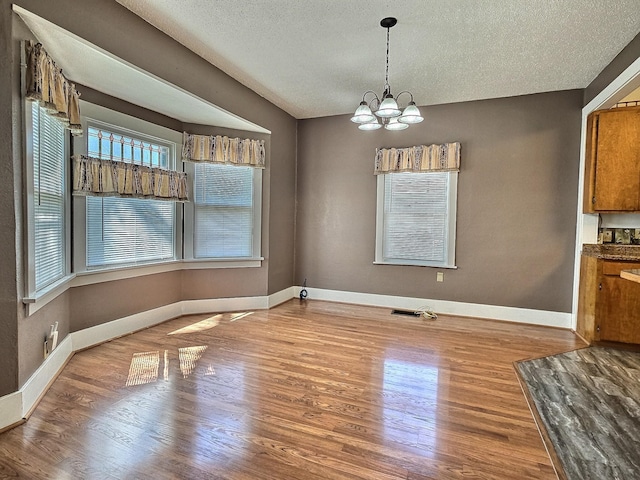 1501 Park St, Fairmont, MN 56031 - unfurnished dining area featuring a chandelier, wood finished floors, a textured ceiling, and baseboards