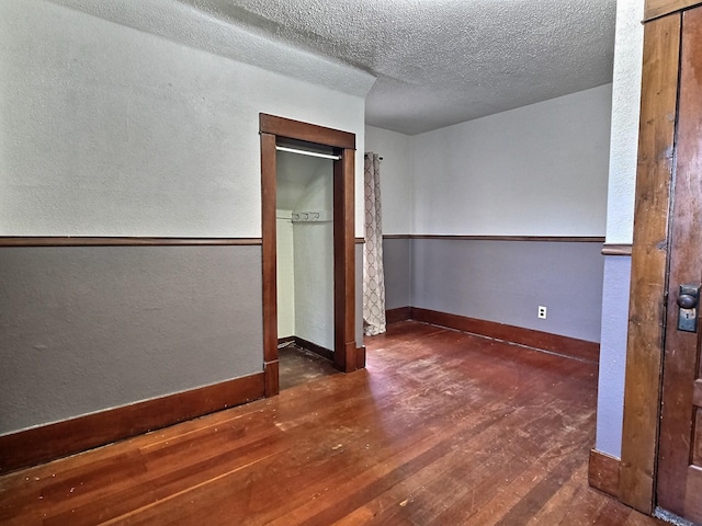 1501 Park St, Fairmont, MN 56031 - unfurnished bedroom with hardwood / wood-style flooring, a textured wall, a textured ceiling, and baseboards