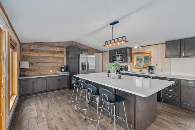 1651 Niles Ln N, Centuria, WI 54824 - kitchen with stainless steel appliances, a breakfast bar, vaulted ceiling, dark wood-type flooring, and a kitchen island
