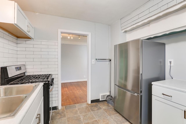kitchen featuring appliances with stainless steel finishes, backsplash, white cabinets, and stone finish floors