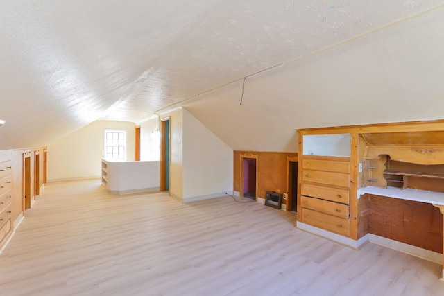 bonus room with wood finished floors, baseboards, vaulted ceiling, and a textured ceiling