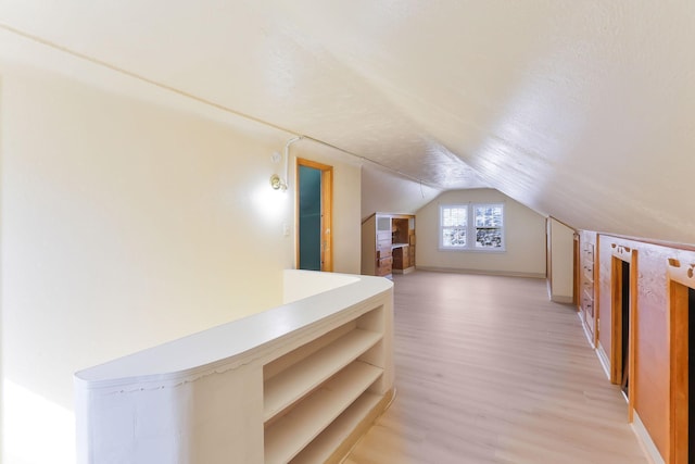 bonus room featuring light wood finished floors, lofted ceiling, and baseboards