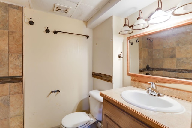 full bath featuring toilet, tiled shower, and vanity