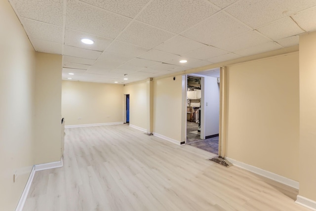 unfurnished room with wood finished floors, recessed lighting, a drop ceiling, and baseboards