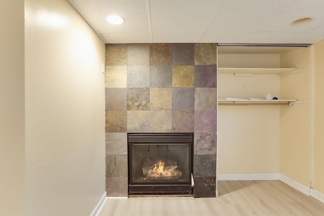 detailed view of wood finished floors, baseboards, a tile fireplace, a drop ceiling, and recessed lighting