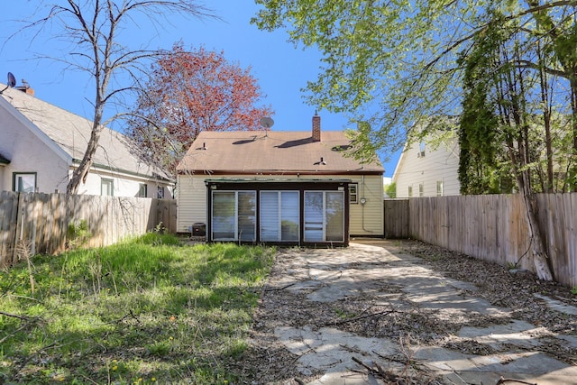 back of property featuring a chimney, a fenced backyard, a patio area, and roof with shingles