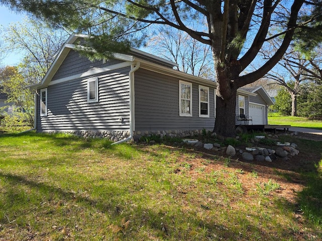 view of side of property featuring a garage and a lawn