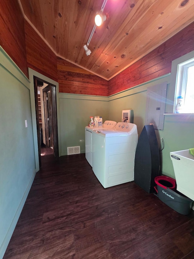 clothes washing area with washing machine and dryer, electric panel, wood finished floors, wooden ceiling, and wooden walls