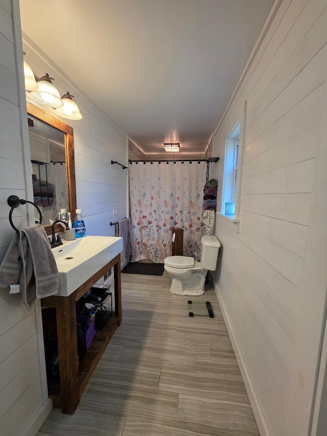 bathroom featuring wood walls, toilet, a shower with shower curtain, vanity, and crown molding