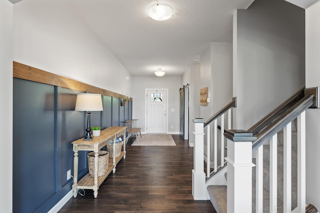 entryway featuring dark wood-style flooring, baseboards, stairs, and a textured ceiling