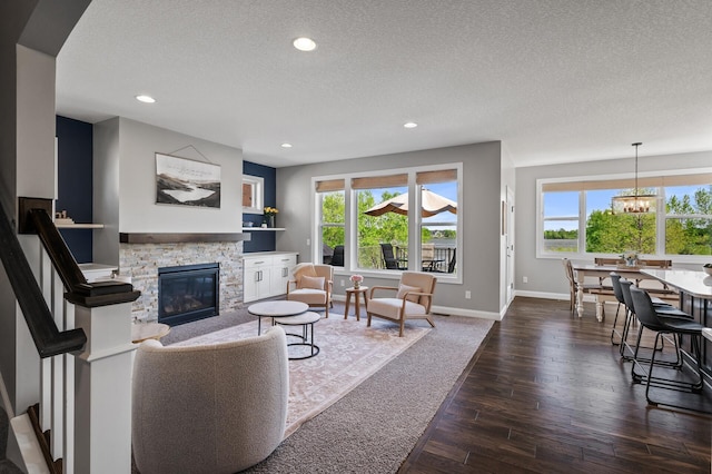 living area with a stone fireplace, healthy amount of natural light, a textured ceiling, recessed lighting, and dark wood-type flooring