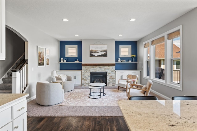 living room featuring dark wood finished floors, stairway, recessed lighting, baseboards, and a fireplace