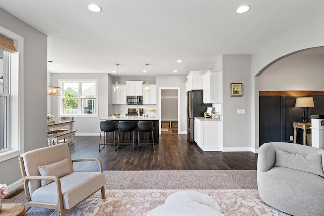 living room with arched walkways, dark wood-style floors, recessed lighting, and baseboards