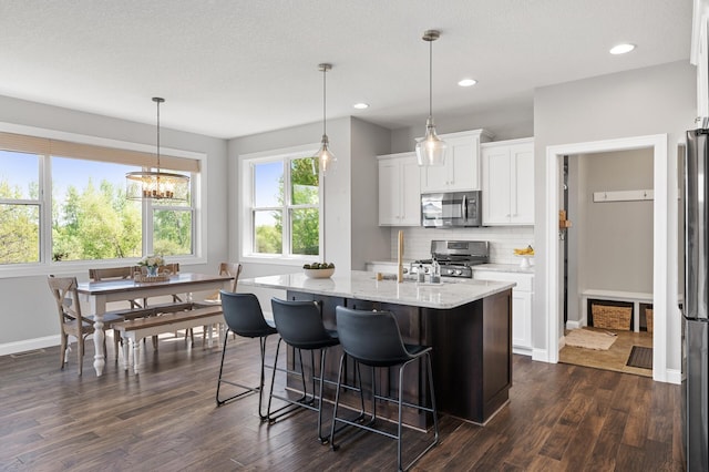 kitchen featuring appliances with stainless steel finishes, dark wood finished floors, decorative backsplash, light stone counters, and recessed lighting