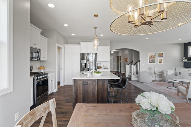 kitchen with stainless steel appliances, dark wood finished floors, open floor plan, a sink, and recessed lighting