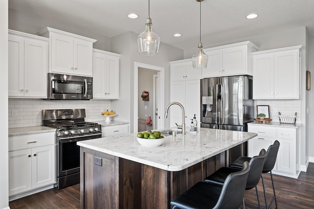kitchen featuring appliances with stainless steel finishes, a sink, dark wood-style floors, recessed lighting, and tasteful backsplash