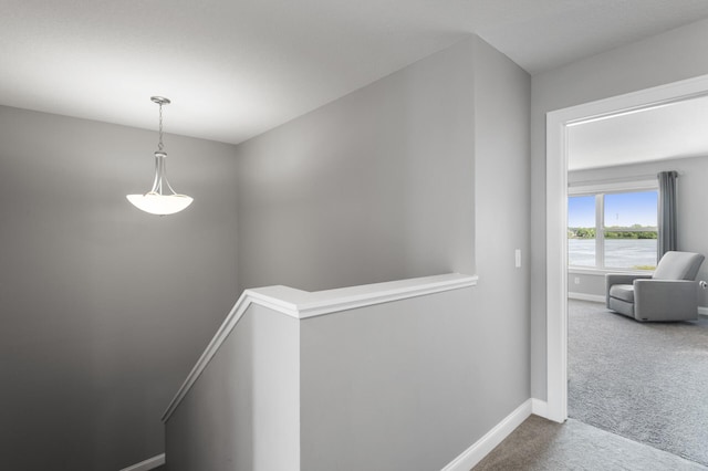 hall featuring an upstairs landing, carpet, and baseboards
