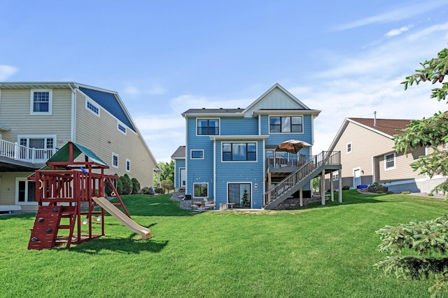 back of house featuring board and batten siding, a yard, a wooden deck, stairway, and a playground